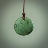 A lovely disc design with cupping on one side and the lightly convex form on the other - a little feature that captures the light and gives the piece a sense of movement and form. Hand made from New Zealand Jade by Ric Moor. Delivered with an adjustable brown cord. 