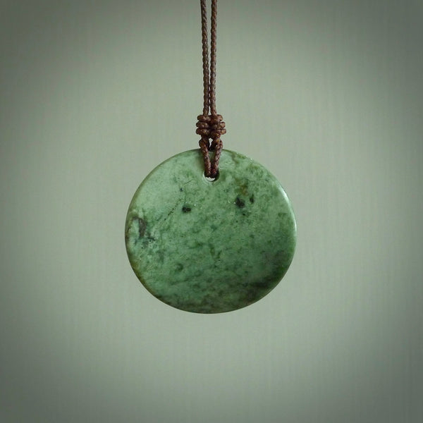 A lovely disc design with cupping on one side and the lightly convex form on the other - a little feature that captures the light and gives the piece a sense of movement and form. Hand made from New Zealand Jade by Ric Moor. Delivered with an adjustable brown cord. 