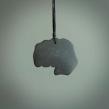 Greywacke Beach Stone fist bump, pendant hand made here in New Zealand. Hand carved by Rhys Hall for NZ Pacific. Handmade jewellery for sale online. The cord is black and has a loop and pebble toggle closure. Unique necklace for men and women. fist pump necklace hand made from New Zealand Greywacke Beach Stone.