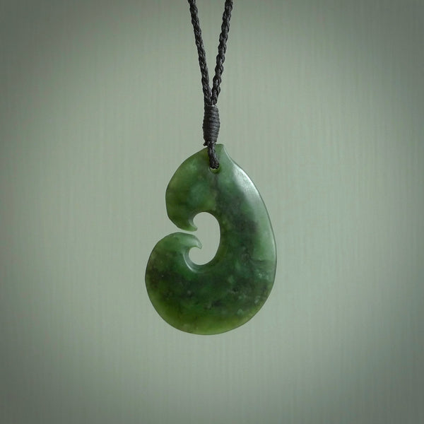 This photo shows a traditional hook pendant. It a a lovely deep green jade. The cord is a four plait black and is adjustable in length. One only, contemporary matau necklace from Jade, by Ric Moor.