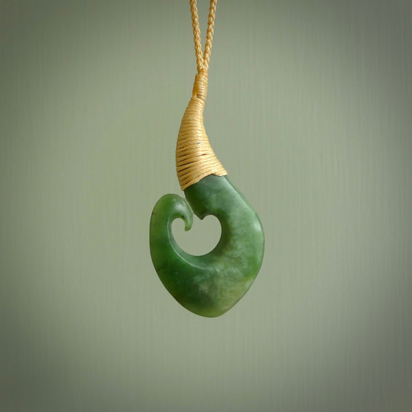 Hand carved jade matau or hook pendant. Carved by New Zealand artist Donna Summers. This matau, is carved from a very striking New Zealand jade. It is both intricate and simple in design - it has hidden folds and smooth curves. A piece to be worn or displayed - the carving and the jade are both magnificent. Hand made by Donna Summers.