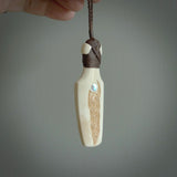 Hand carved engraved bone toki necklace hand made here in New Zealand. One only artistic toki pendant with hand plaited dark brown adjustable cord. Shipped to you with Express Courier. Stand out toki pendant for men and women. Bone Toki with engraved spiral on the back and paua shell insert on the front.