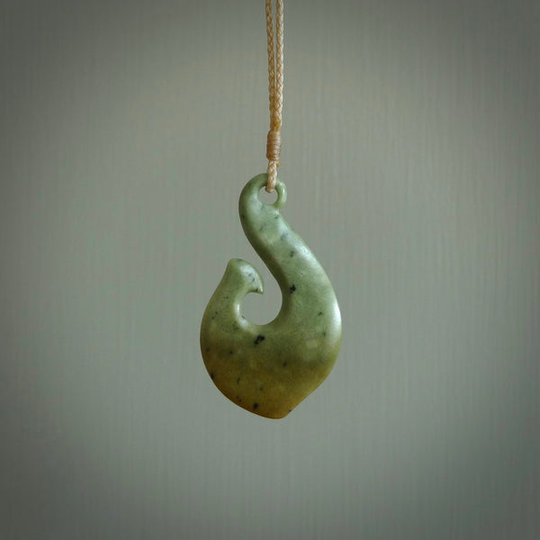This picture shows a jade hook pendant, also called a hei-matau, carved for us in New Zealand jade. The jade is a wonderful deep mint green pounamu. This is a rare jade loved and valued for its distinctive colour. The carver is Ric Moor - and this is a beautiful example of his work. The cord is a four-plait, adjustable brown coloured necklace.