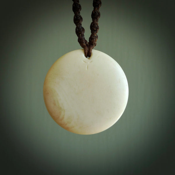 This photo shows a medium sized yin and yang pendant hand carved from bone with Mother of Pearl, Lapis Lazuli and Paua Shell inlay and brass. This is a stand out one off necklace for those who appreciate art to wear. It is provided with a cord in black that is a fixed length with Paua Shell Toggle. We ship this piece worldwide and shipping is included in the price.