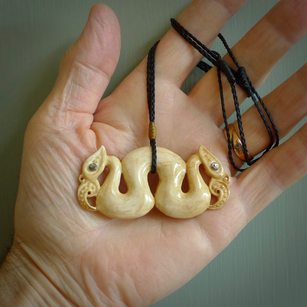 This is a unique double manaia, pekapeka, handcarved bone pendant from cow bone. The cord is Black and is length adjustable. This is delivered to you with Express Courier. The eyes are made from Paua shell.