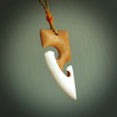 A hand carved bone toki with double koru, intricate pendant. The cord is a tan colour and is adjustable. A medium sized hand made toki with koru necklace by New Zealand artist Tonijae Brockway. Tonijae has stained parts of the bone which really add to the dimension of this pendant. One off work of art to wear.