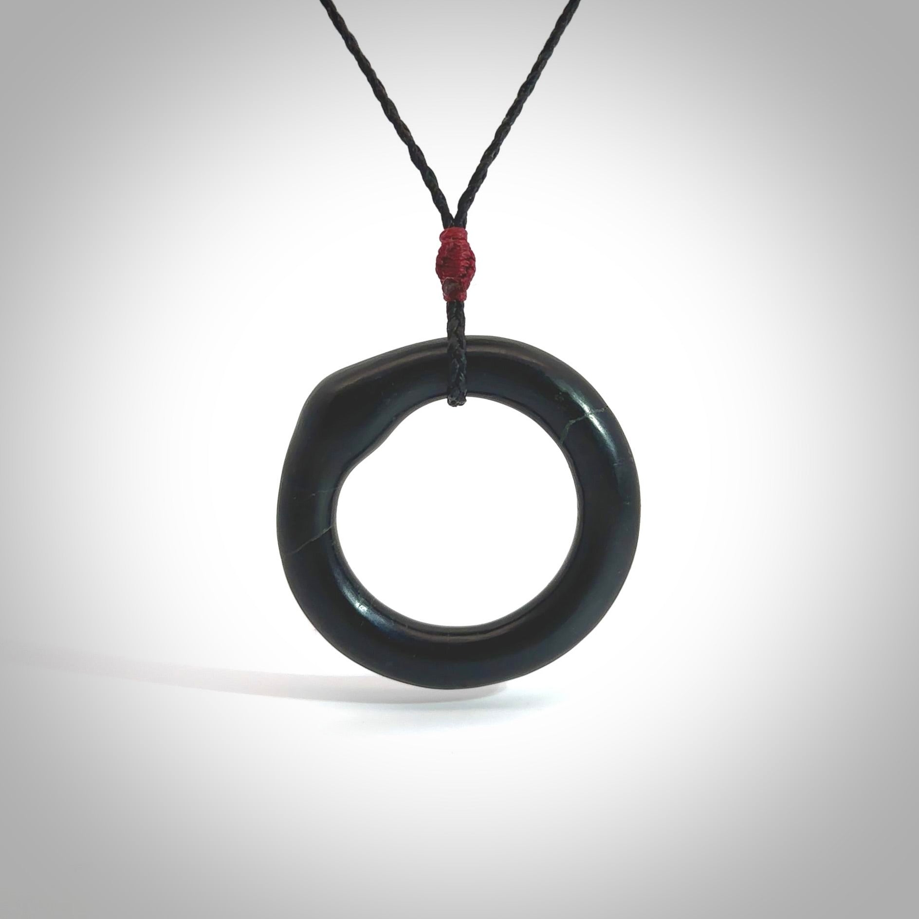 This picture shows a hand carved black jade circle pendant with sterling silver inlay. It is suspended from an adjustable Black cord. Delivery is free worldwide.