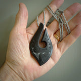A hand carved large New Zealand Tangiwai Hook, Matau, necklace. The cord is a cosmos and blue moon grey colour and is length adjustable. A large sized hand made hook necklace by New Zealand artist Rueben Tipene. One off work of art to wear.