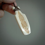 Hand carved engraved bone toki necklace hand made here in New Zealand. One only artistic toki pendant with hand plaited dark brown adjustable cord. Shipped to you with Express Courier. Stand out toki pendant for men and women. Bone Toki with engraved spiral on the back and paua shell insert on the front.