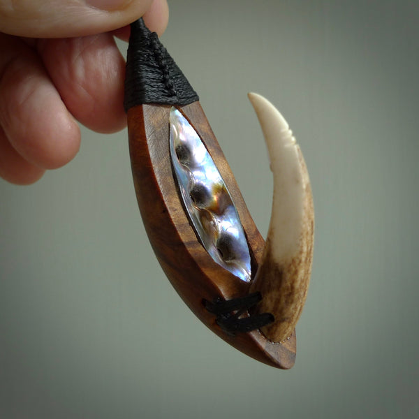 This picture shows a large matau, hook called a pā kahawai. It is carved from deer antler bone, wood, and paua shell. One only, free shipping worldwide. Provided with an adjustable black cord. Stunning work of Art to Wear by Fumio Noguchi.