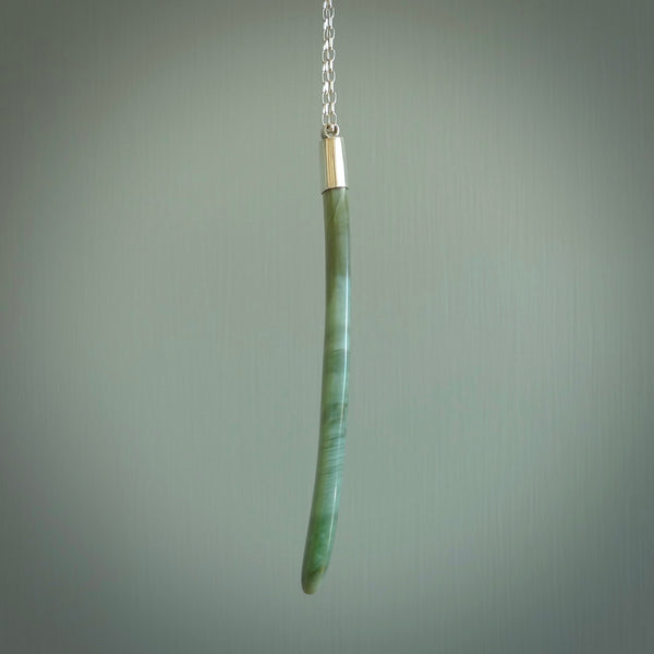 This picture shows a hand carved Inanga Pounamu, jade drop pendant with sterling silver cap and chain. The jade is a very dark green with a shimmer of light blue tones in the stone. It is suspended from a sterling silver clasp and we supply a sterling silver chain. Delivery is free worldwide.