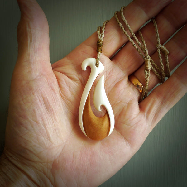 A hand carved bone hook pendant. The cord is a Tan colour and is adjustable. A medium sized hand made hook necklace by New Zealand artist Tonijae Brockway. Tonijae has stained parts of the bone which really add to the dimension of this pendant. One off work of art to wear.
