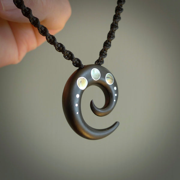 This photo shows a medium horn koru pendant hand carved from horn with premium nz paua shell, Australian Golden and Tahitian Black Mother of Pearl alongside; brass, copper and silver. This is a stand out one off necklace for those who appreciate art to wear. It is provided with a cord in black that is a fixed length with Paua Shell Toggle. We ship this piece worldwide and shipping is included in the price.