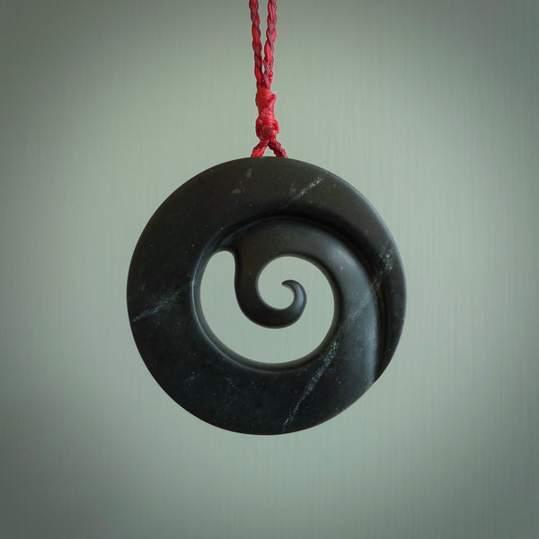 Hand made large New Zealand Pounamu, Jade Koru pendant. Hand carved in New Zealand by Rueben Tipene. Hand made jewellery. Unique large Greenstone Koru with adjustable juicy red/passion red cord. Free shipping worldwide.