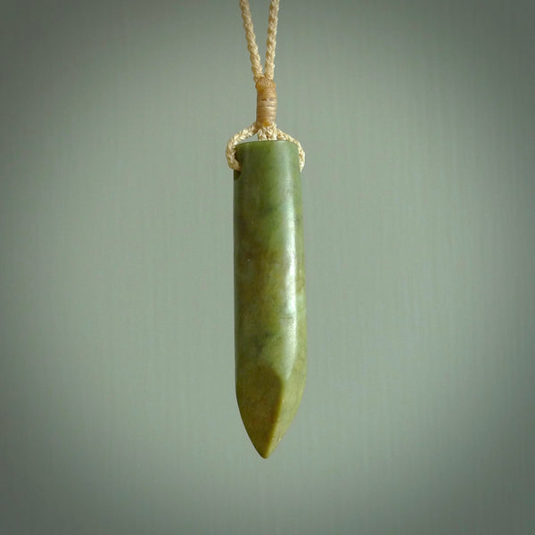 This picture shows a hand carved flower jade drop pendant by Ric Moor. The jade is a wonderful green with a shimmer of orange tones in the stone. It is suspended from a beige adjustable cord. Delivery is free worldwide.