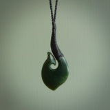 This picture shows a large deep green large jade hook pendant, also called a hei-matau, carved for us in New Zealand jade. The carver is Donna Summers - and this is a beautiful example of his work. The cord is a four-plait, adjustable black coloured necklace.