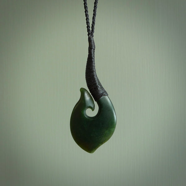This picture shows a large deep green large jade hook pendant, also called a hei-matau, carved for us in New Zealand jade. The carver is Donna Summers - and this is a beautiful example of his work. The cord is a four-plait, adjustable black coloured necklace.