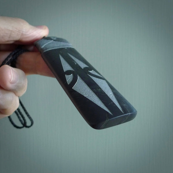 This photo shows a large Argillite, Pakohe Stone Toki shaped pendant. It a a lovely, black stone. The cord is black and is adjustable in length. One only large, contemporary Toki necklace from Jade, by Rueben Tipene.