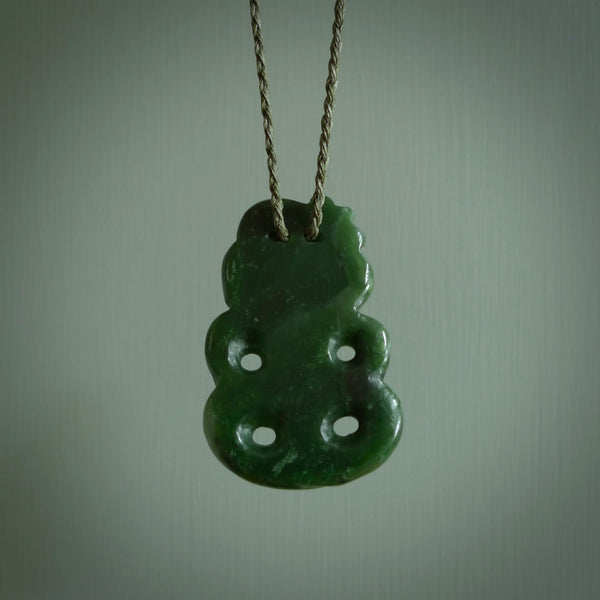 This is a medium sized tiki - carved from gorgeous Marsden jade. The craftsmanship is superb, this piece is as well carved as any we have seen. The cord is an adjustable plaited cord in black.