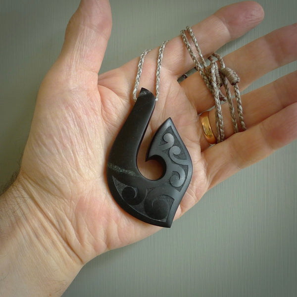 A hand carved large New Zealand Tangiwai Hook, Matau, necklace. The cord is a mushroom and snowstorm grey colour and is length adjustable. A large sized hand made hook necklace by New Zealand artist Rueben Tipene. One off work of art to wear.