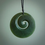 This picture shows a large hand carved jade koru pendant. It is a darker green colour which is quite translucent where the jade is thin. Although a large piece, it is a wonderful, delicate piece of jewellery. The cord is hand plaited and adjustable so that you can position the pendant where it suits you best. This koru was carved for us by Donna Summers. Delivery is free worldwide.