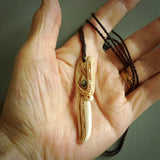 This picture shows a carved kāhu, hawk in bone. It is a drop shaped pendant. The artist has carved traditional decorative kowhaiwhai designs into the body and these run up the sides of the hawk. These have specific meanings. It is provided with a hand-plaited brown cord that is length adjustable. Shipping is included and we ship worldwide.