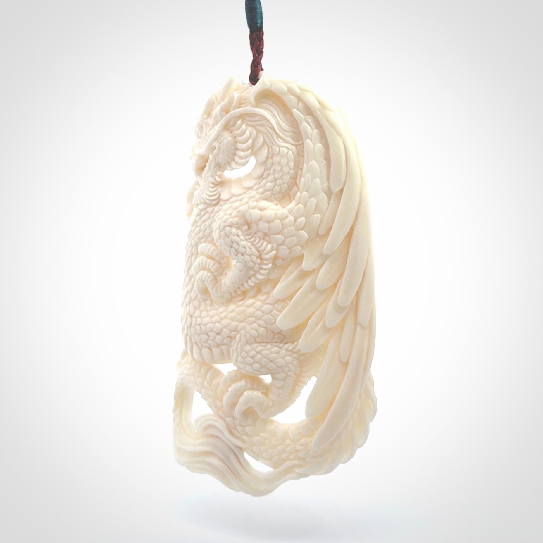 This is a hand carved bone dragon pendant. It is made from bone and has an adjustable Plum coloured cord. This is a large sized necklace and is a very unique, one only, pendant that is a piece for art lovers.