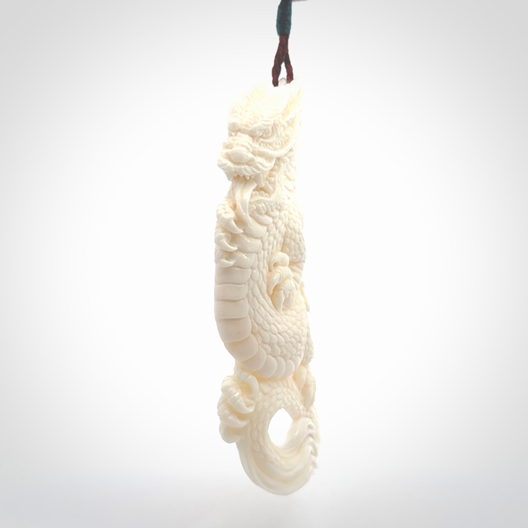 This is a hand carved bone dragon pendant. It is made from bone and has an adjustable Plum coloured cord. This is a large sized necklace and is a very unique, one only, pendant that is a piece for art lovers.