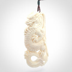 This is a hand carved bone dragon pendant. It is made from bone and has an adjustable Plum coloured cord. This is a large sized necklace and is a very unique, one only, pendant that is a piece for art lovers.