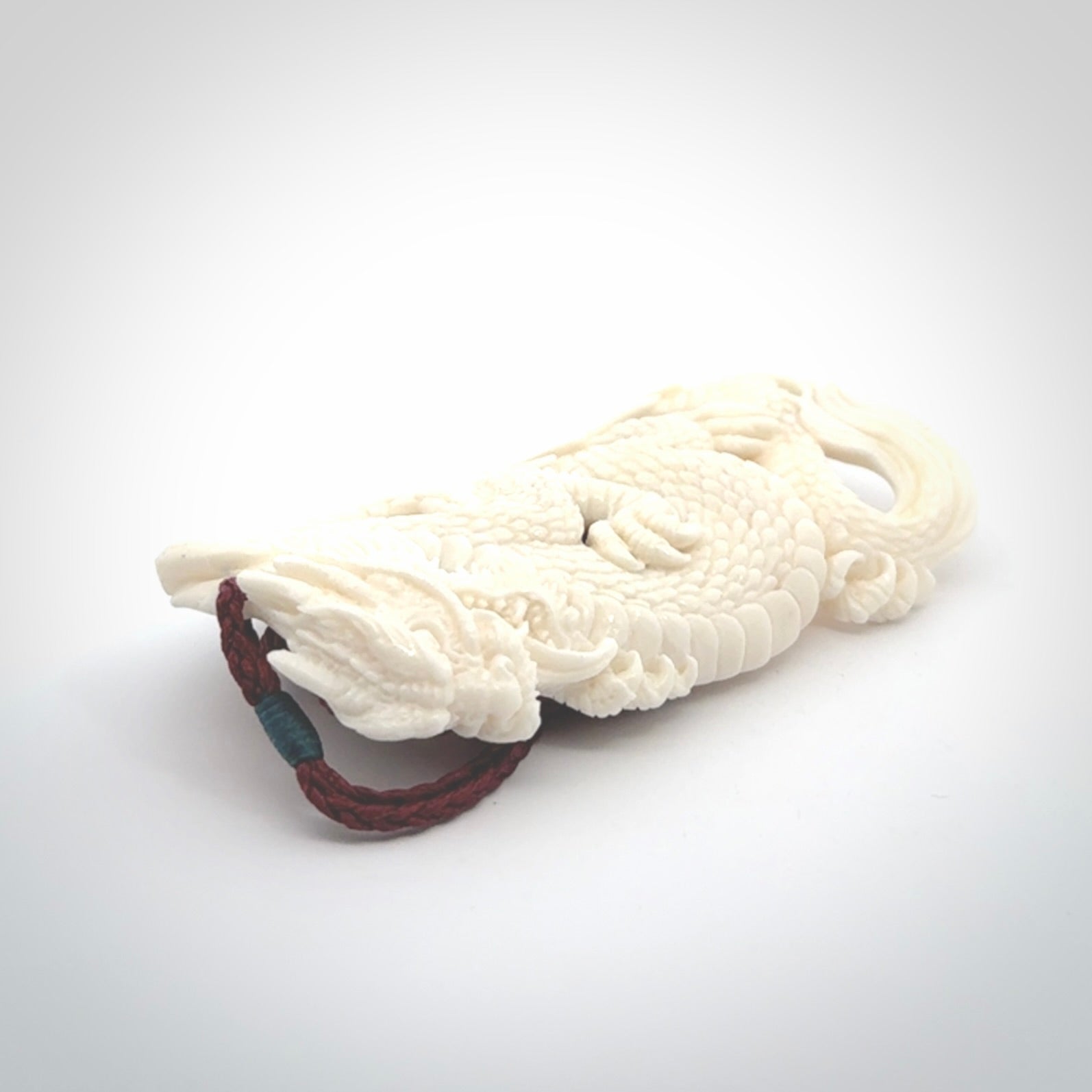This is a hand carved bone dragon pendant. It is made from bone and has an adjustable Plum coloured cord. This is a large sized necklace and is a very unique, one only, pendant that is a piece for art lovers.