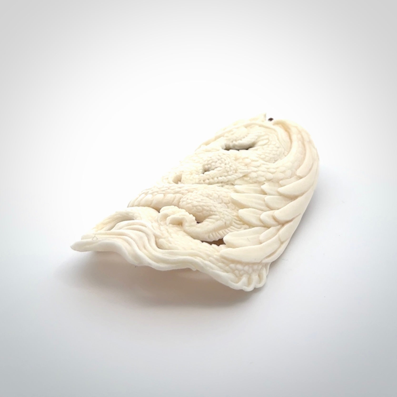 This is a hand carved bone dragon pendant. It is made from bone and has an adjustable Plum coloured cord. This is a large sized necklace and is a very unique, one only, pendant that is a piece for art lovers.