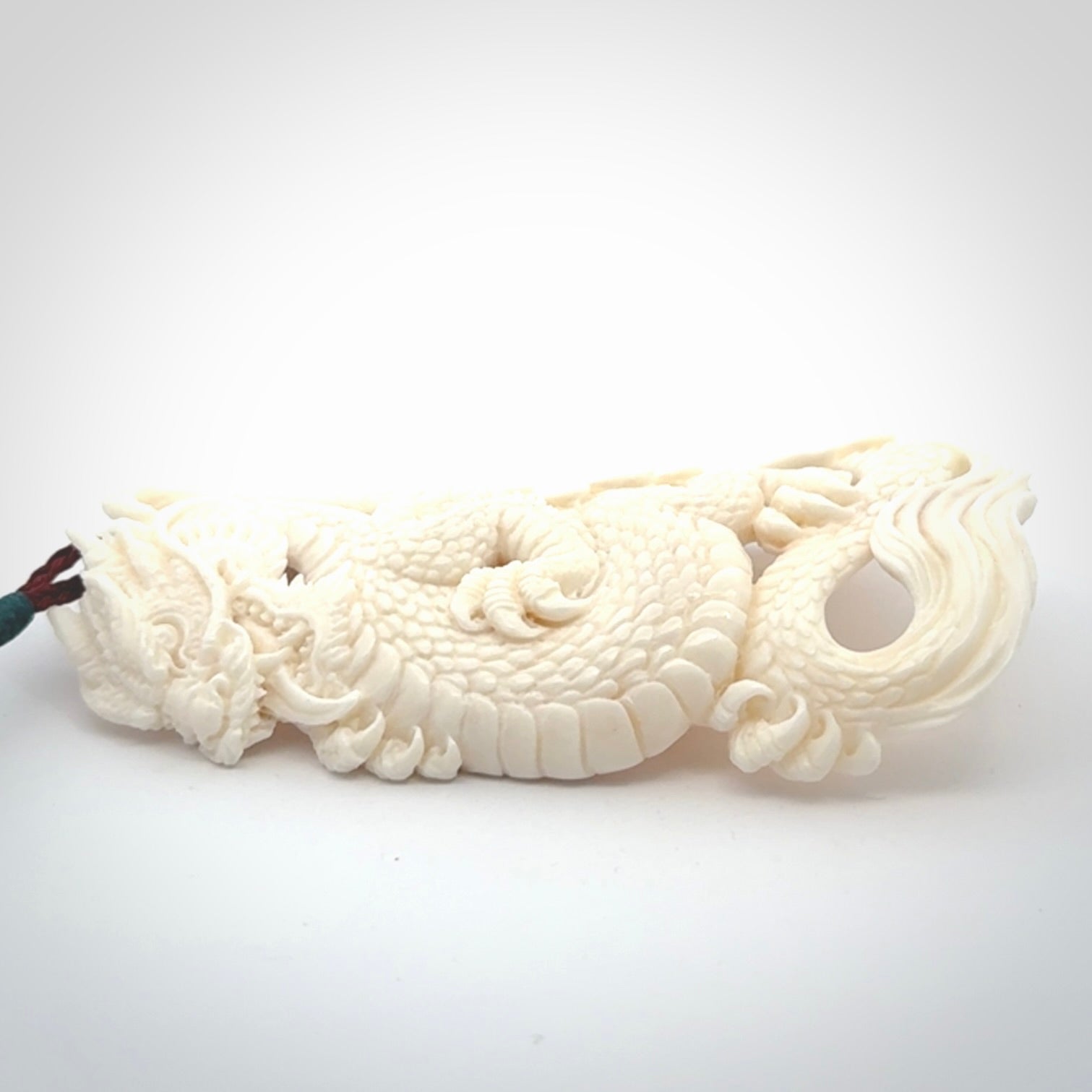 This is a hand carved bone dragon pendant. It is made from bone and has an adjustable Plum coloured cord. This is a large sized necklace and is a very unique, one only, pendant that is a piece for art lovers.
