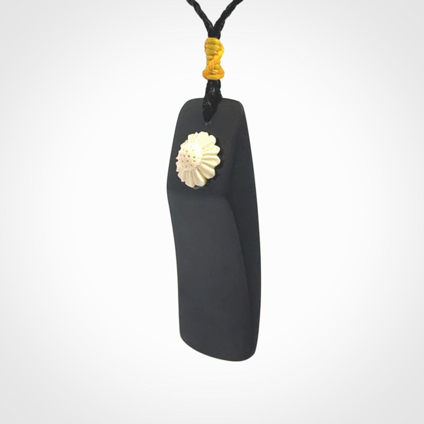Black Jade toki pendant with bone flower. We've bound it with an adjustable black cord and yellow floret.