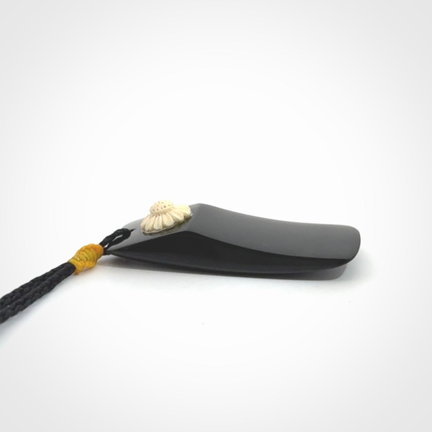 Black Jade toki pendant with bone flower. We've bound it with an adjustable black cord and yellow floret.
