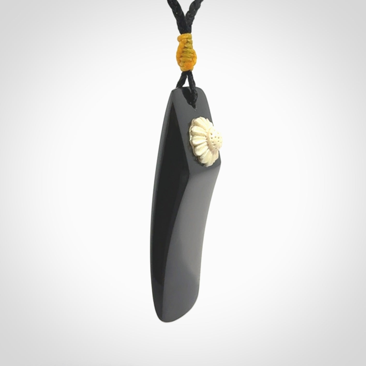 Black Jade toki pendant with bone flower. We've bound it with an adjustable black cord and yellow floret.