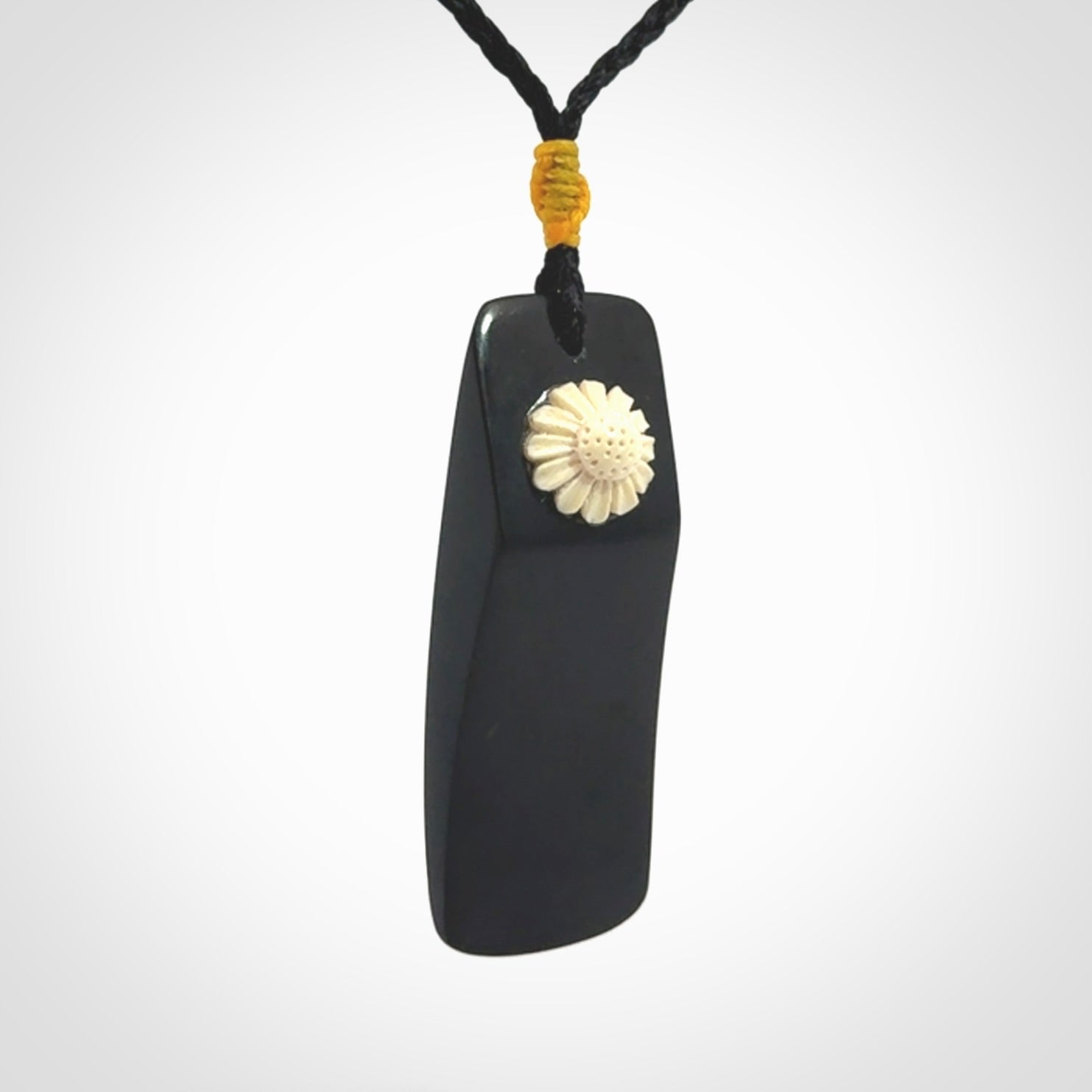Black Jade toki pendant with bone flower. We've bound it with an adjustable black cord and yellow floret.