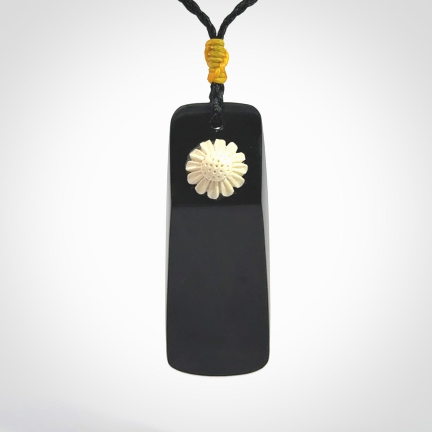 Black Jade toki pendant with bone flower. We've bound it with an adjustable black cord and yellow floret.