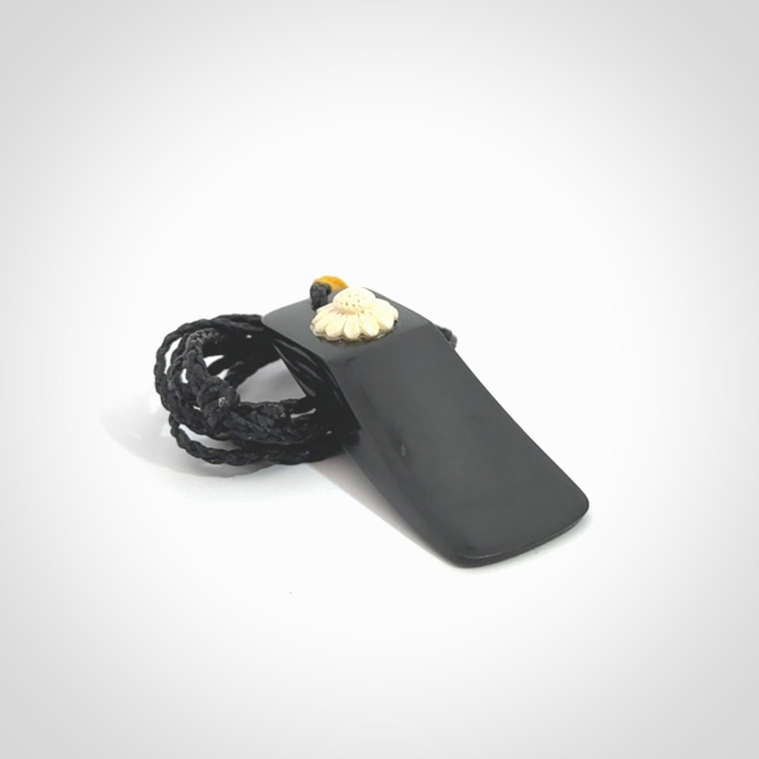 Black Jade toki pendant with bone flower. We've bound it with an adjustable black cord and yellow floret.