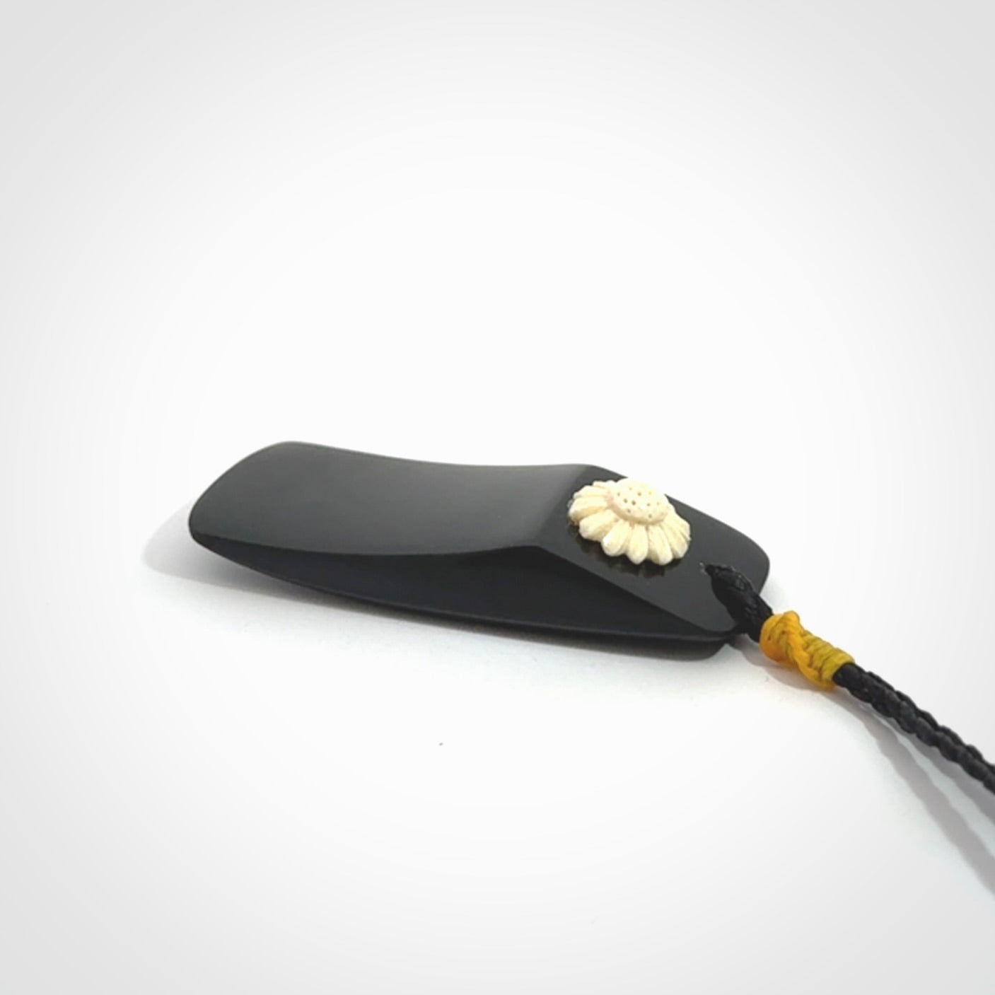 Black Jade toki pendant with bone flower. We've bound it with an adjustable black cord and yellow floret.