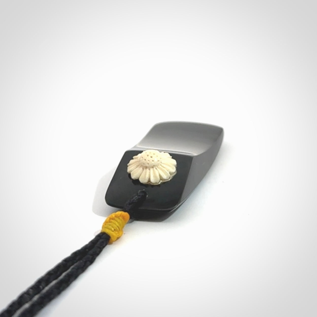 Black Jade toki pendant with bone flower. We've bound it with an adjustable black cord and yellow floret.