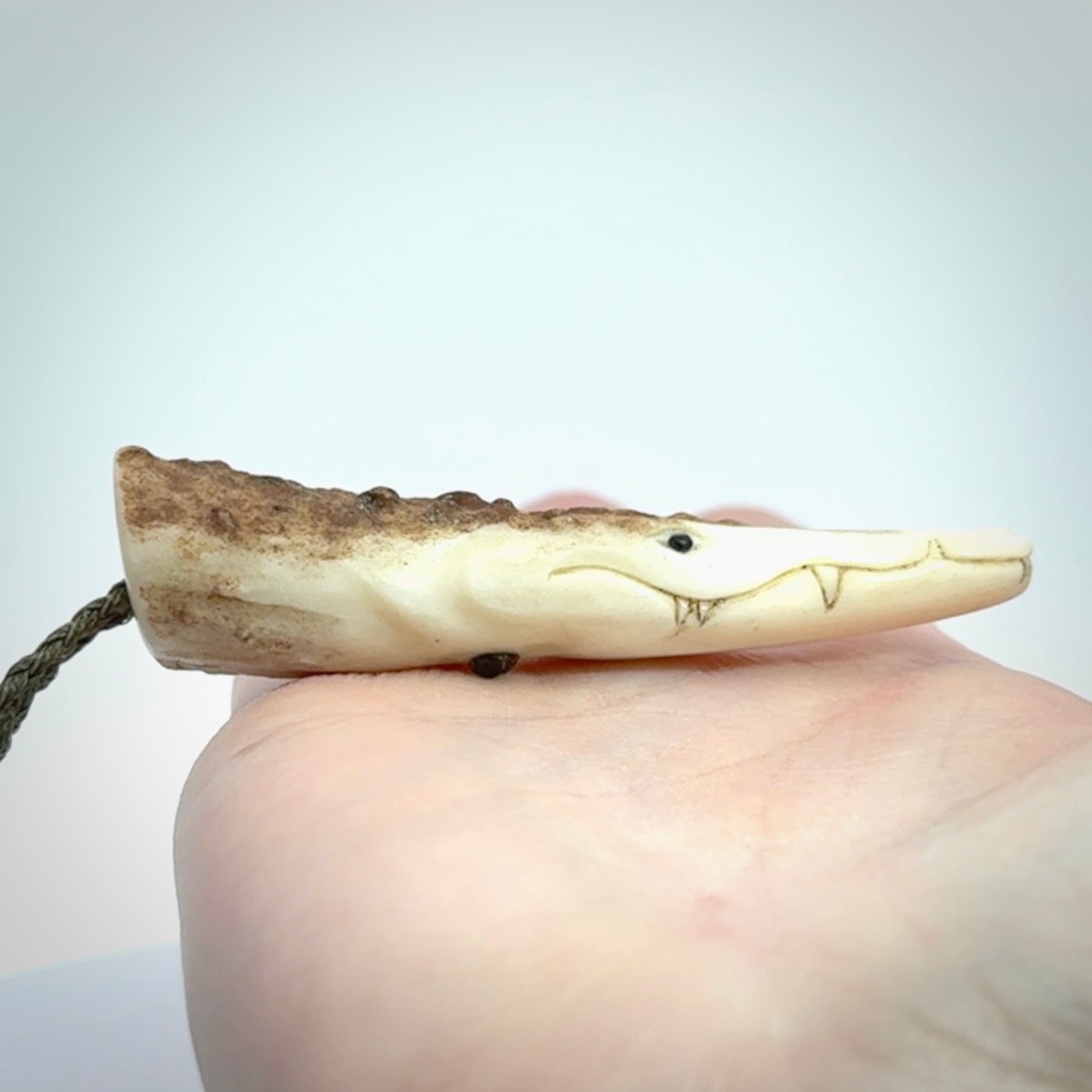 A hand carved crocodile pendant carved from a piece of deer antler. This is a work of art carved by Fumio Noguchi who is renowned for his skill in bone carving.