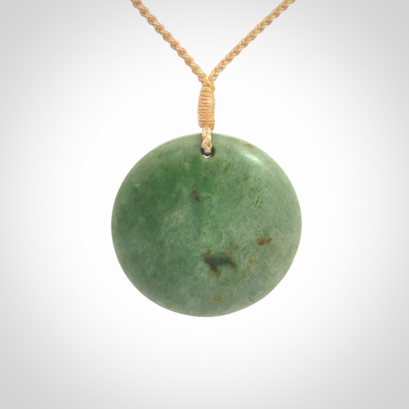 This pendant is a medium sized and cupped koru necklace carved from a lovely light green piece of New Zealand Marsden Jade.