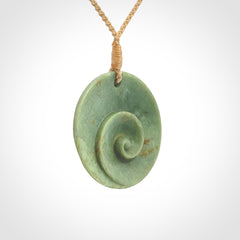 This pendant is a medium sized and cupped koru necklace carved from a lovely light green piece of New Zealand Marsden Jade.