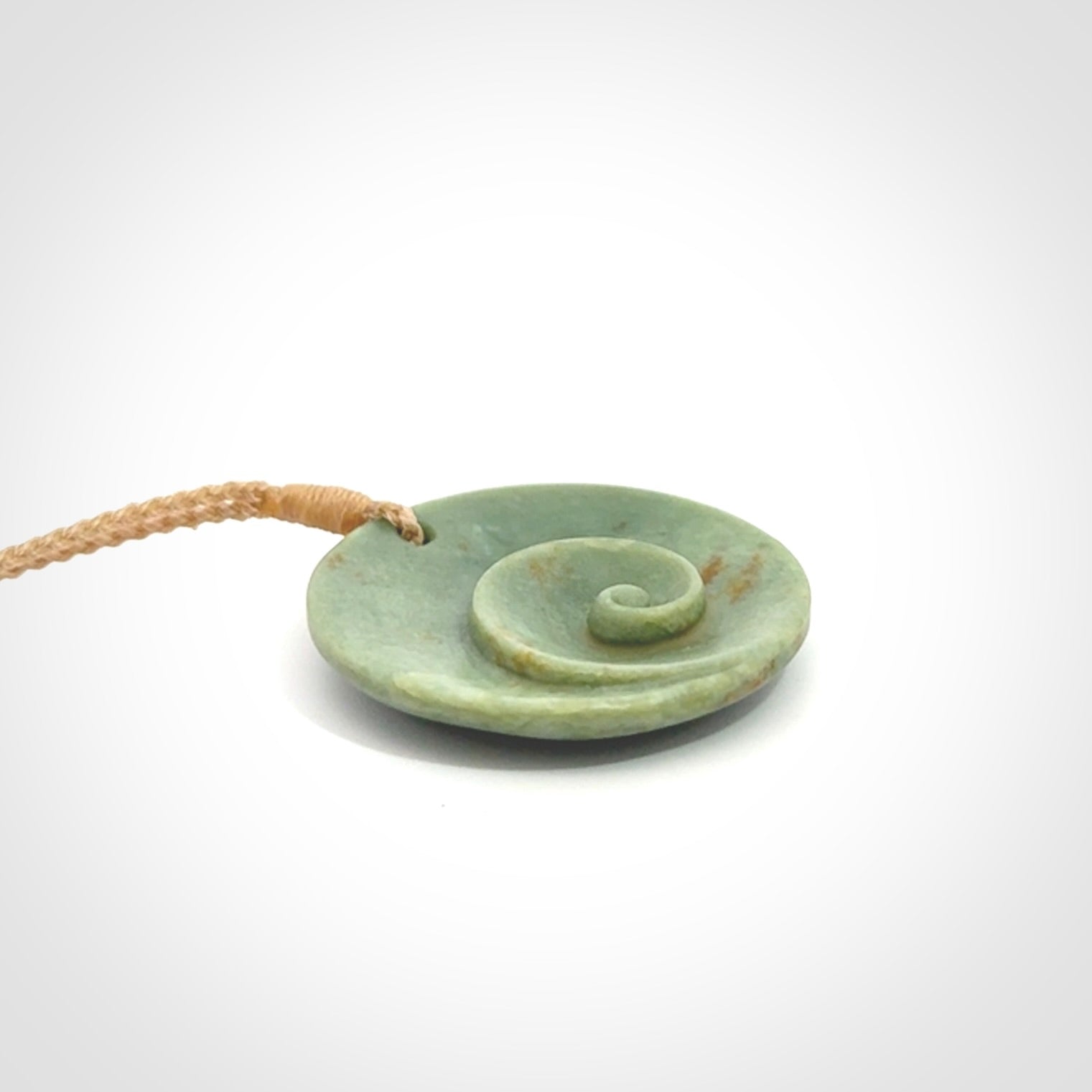 This pendant is a medium sized and cupped koru necklace carved from a lovely light green piece of New Zealand Marsden Jade.