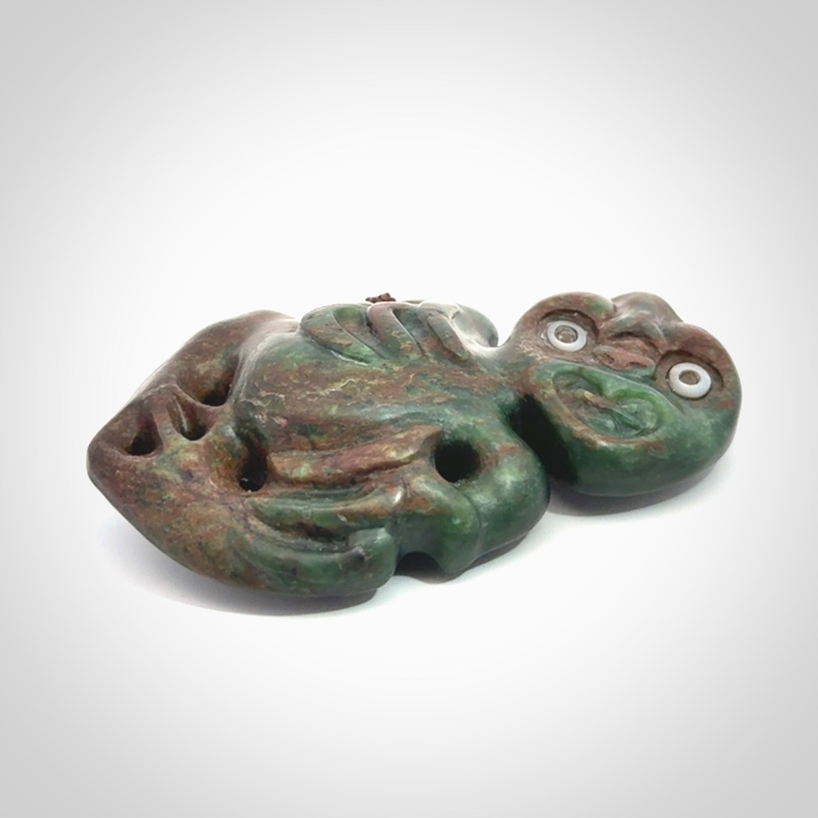 This is a large sized tiki - carved from gorgeous Marsden jade with Pāua Shell eyes. The craftsmanship is superb, this piece is as well carved as any we have seen. We have plaited an adjustable brown cord for this piece.&nbsp;