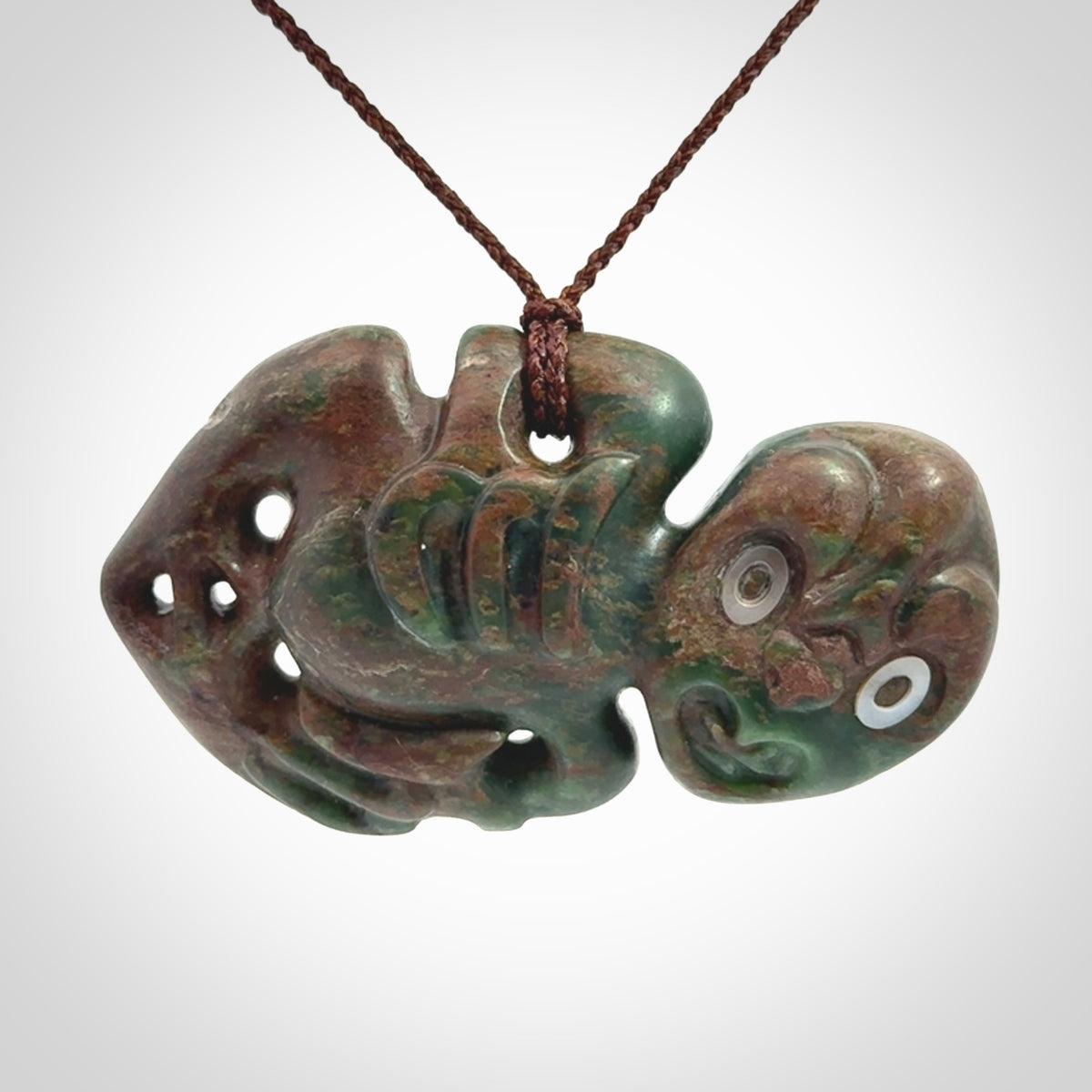 This is a large sized tiki - carved from gorgeous Marsden jade with Pāua Shell eyes. The craftsmanship is superb, this piece is as well carved as any we have seen. We have plaited an adjustable brown cord for this piece.&nbsp;