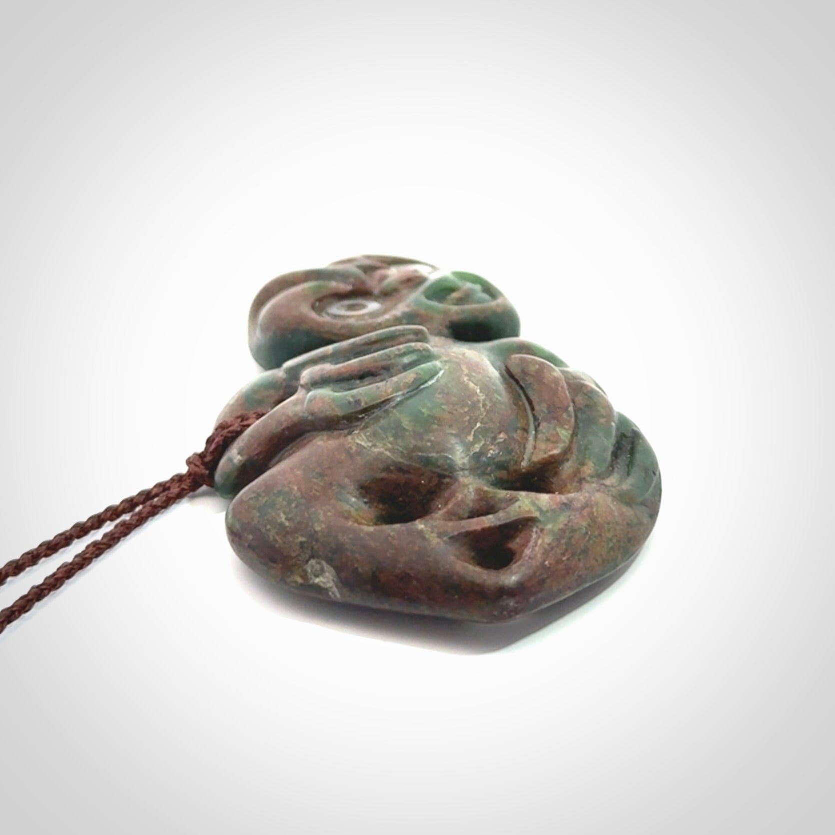 This is a large sized tiki - carved from gorgeous Marsden jade with Pāua Shell eyes. The craftsmanship is superb, this piece is as well carved as any we have seen. We have plaited an adjustable brown cord for this piece.&nbsp;