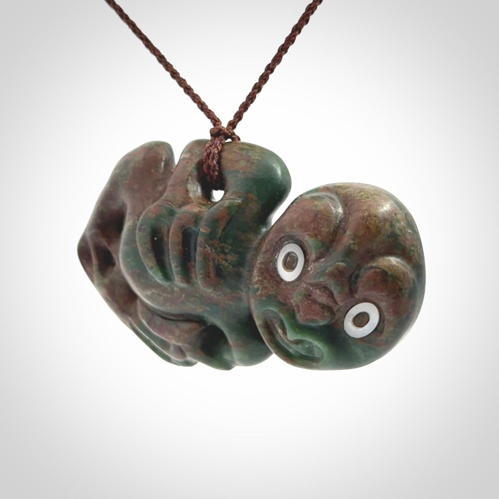 This is a large sized tiki - carved from gorgeous Marsden jade with Pāua Shell eyes. The craftsmanship is superb, this piece is as well carved as any we have seen. We have plaited an adjustable brown cord for this piece.&nbsp;