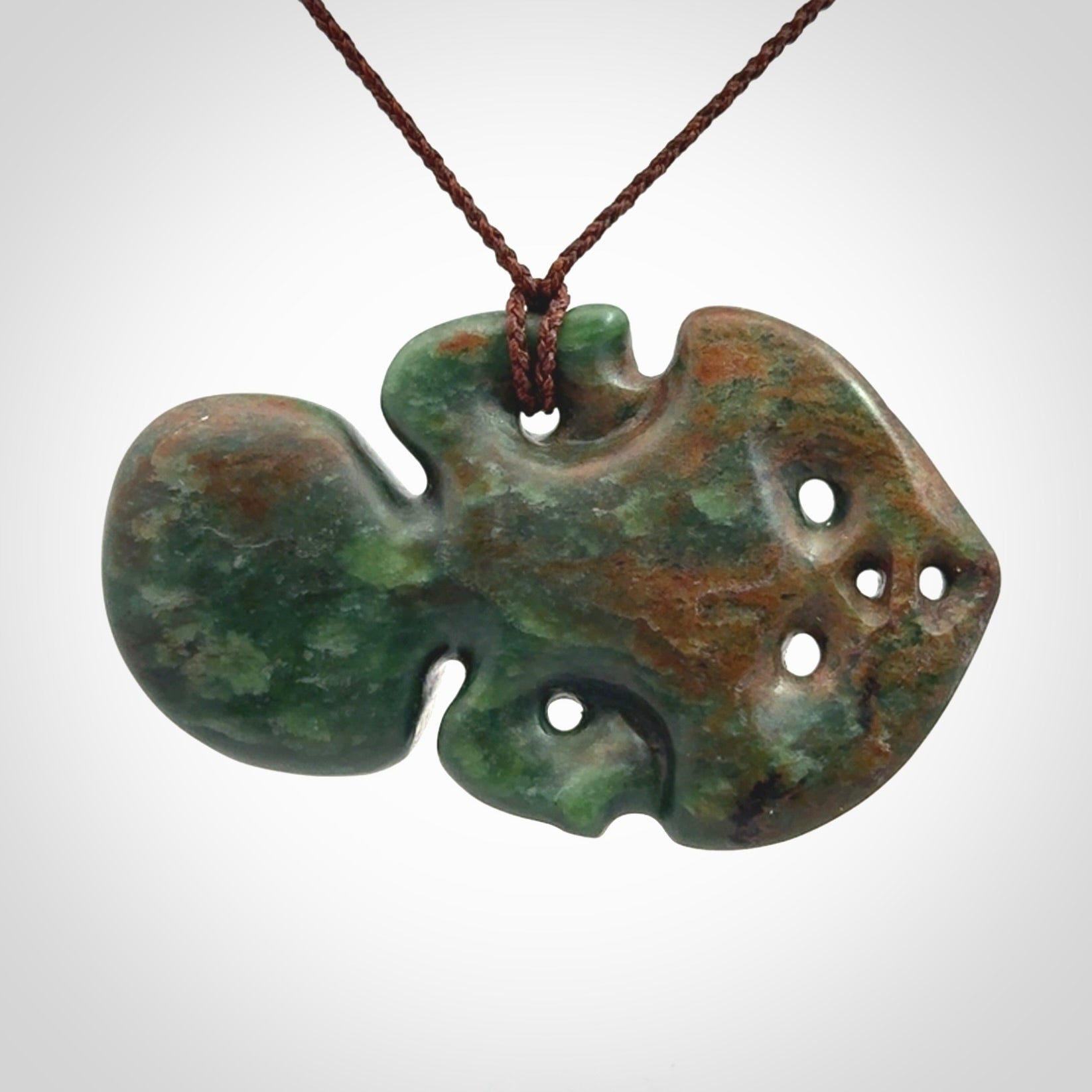 This is a large sized tiki - carved from gorgeous Marsden jade with Pāua Shell eyes. The craftsmanship is superb, this piece is as well carved as any we have seen. We have plaited an adjustable brown cord for this piece.&nbsp;