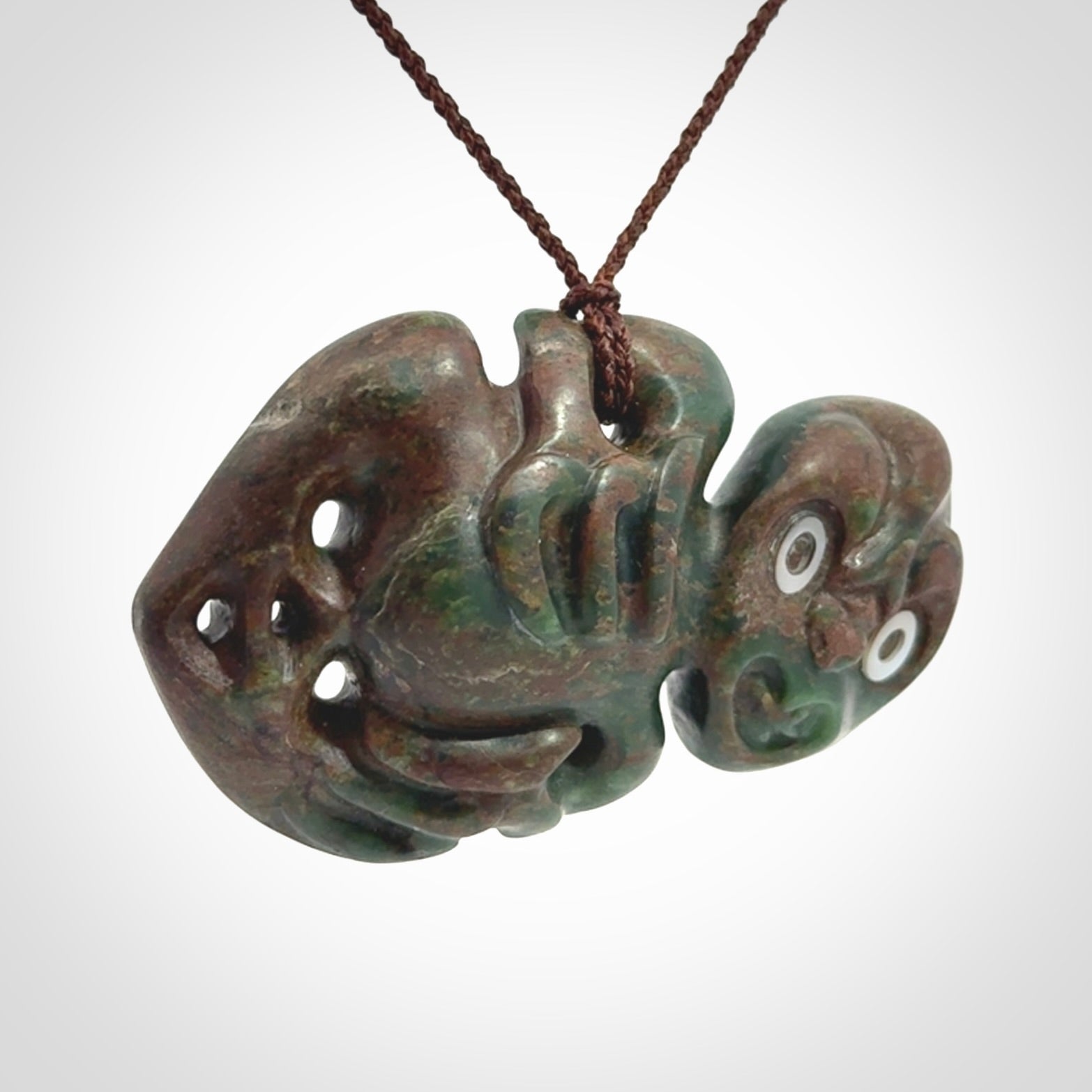 This is a large sized tiki - carved from gorgeous Marsden jade with Pāua Shell eyes. The craftsmanship is superb, this piece is as well carved as any we have seen. We have plaited an adjustable brown cord for this piece.&nbsp;